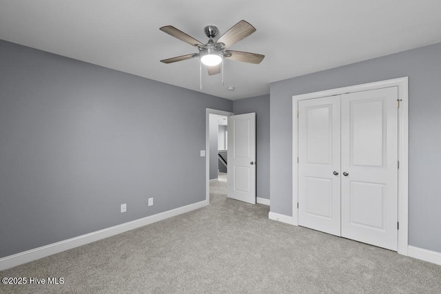 unfurnished bedroom featuring ceiling fan, a closet, and light carpet