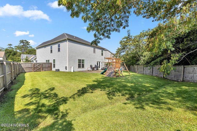 rear view of property featuring a playground and a lawn