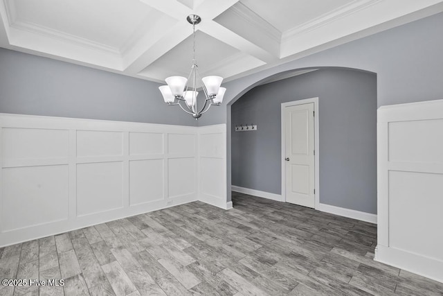 unfurnished dining area featuring beamed ceiling, crown molding, coffered ceiling, and an inviting chandelier