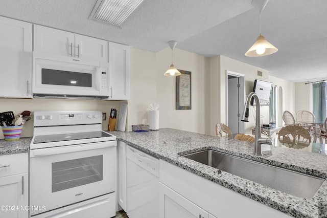 kitchen featuring white appliances, sink, hanging light fixtures, a textured ceiling, and white cabinetry