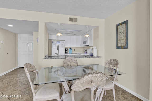 dining room featuring a textured ceiling, light tile patterned flooring, and sink