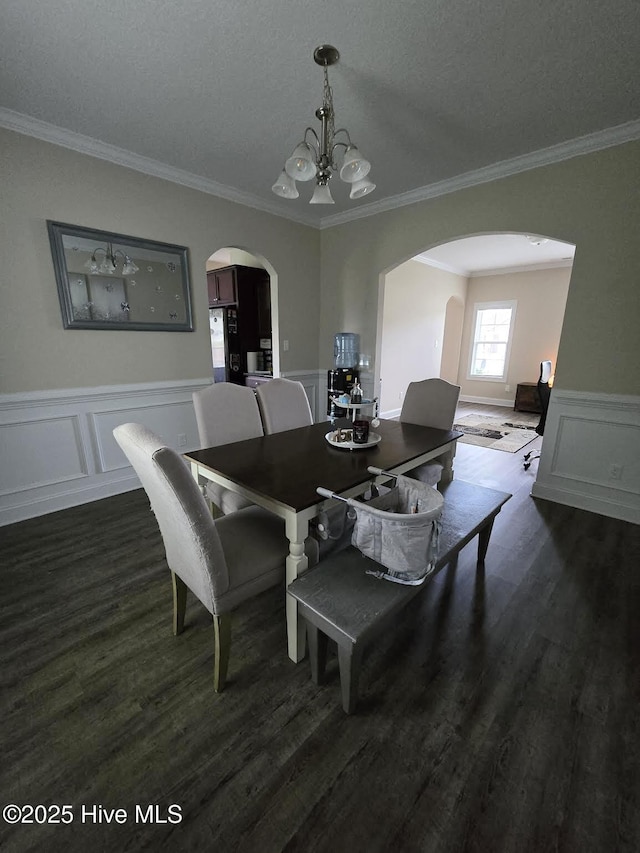 206 Messenger Ct, Jacksonville, NC 28546 - dining room featuring a chandelier, arched walkways, dark wood-type flooring, crown molding, and a decorative wall