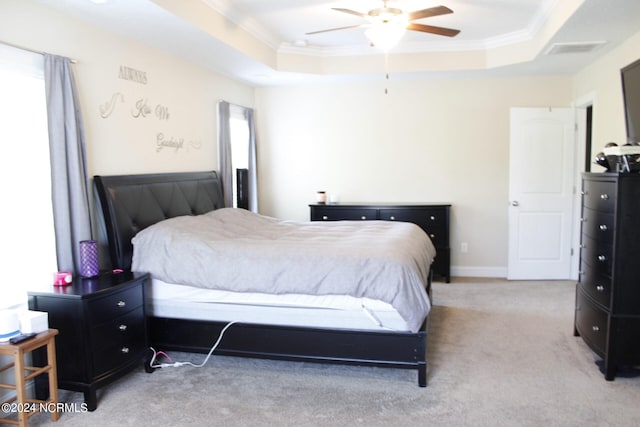 carpeted bedroom with a raised ceiling, ceiling fan, and ornamental molding