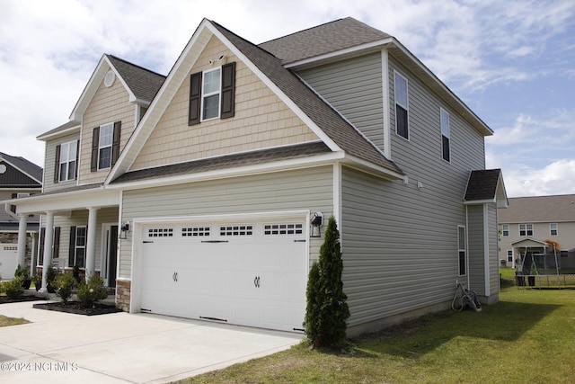 view of front facade with an attached garage, driveway, a shingled roof, and a front yard