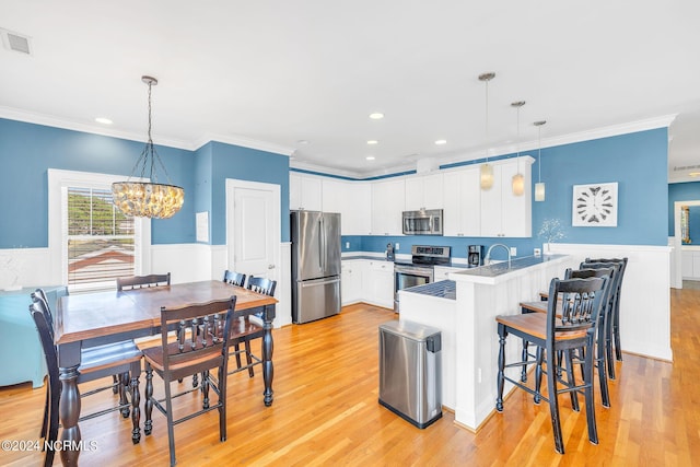 kitchen featuring kitchen peninsula, white cabinetry, stainless steel appliances, and decorative light fixtures