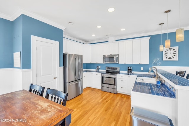 kitchen with sink, hanging light fixtures, stainless steel appliances, crown molding, and white cabinets