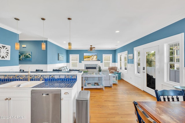 kitchen with white cabinetry, dishwasher, hanging light fixtures, light hardwood / wood-style floors, and ornamental molding