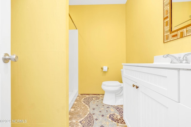 bathroom featuring toilet, vanity, and walk in shower