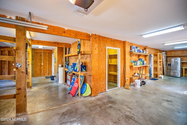 garage with wooden walls and stainless steel refrigerator with ice dispenser