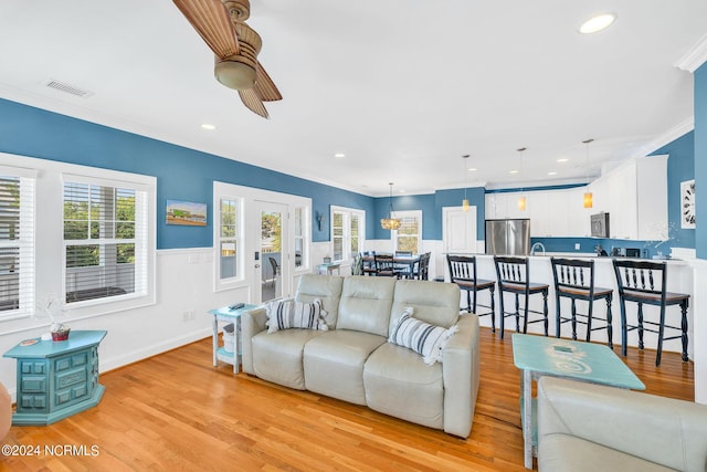 living room featuring ceiling fan, light hardwood / wood-style flooring, and crown molding