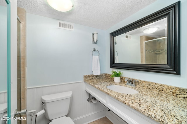 bathroom with toilet, a shower with shower door, sink, and a textured ceiling