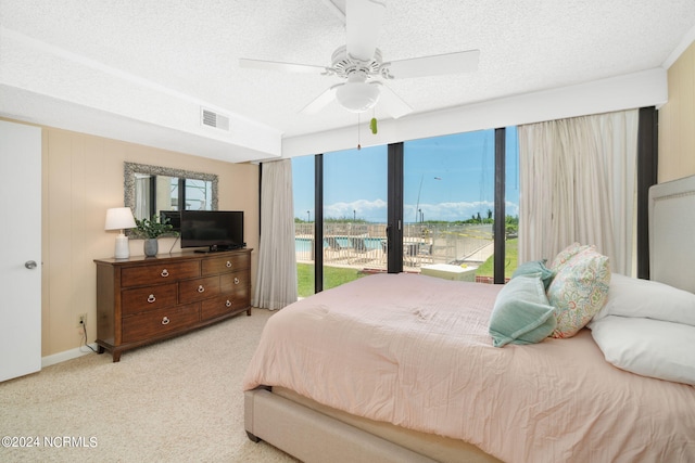 carpeted bedroom with access to exterior, multiple windows, and a textured ceiling