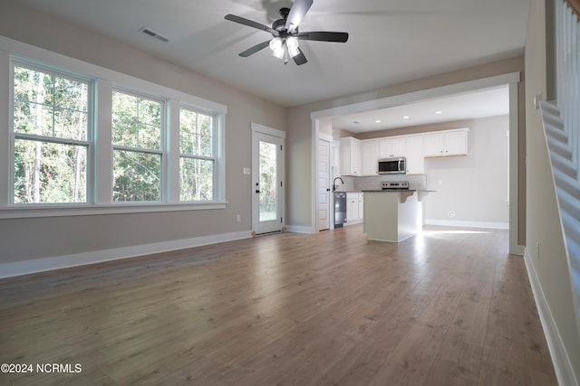 unfurnished living room featuring dark wood-type flooring and ceiling fan