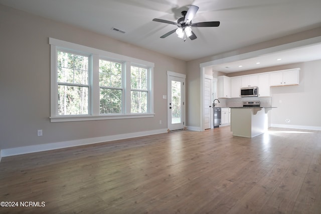 unfurnished living room with hardwood / wood-style floors, ceiling fan, and plenty of natural light