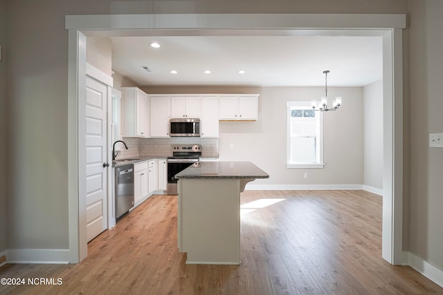 kitchen with light hardwood / wood-style flooring, a center island, white cabinets, and stainless steel appliances