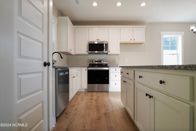 kitchen with white cabinetry, appliances with stainless steel finishes, light hardwood / wood-style flooring, and decorative backsplash