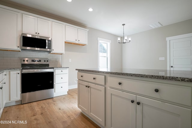 kitchen featuring stainless steel appliances, light stone countertops, pendant lighting, white cabinetry, and light hardwood / wood-style floors