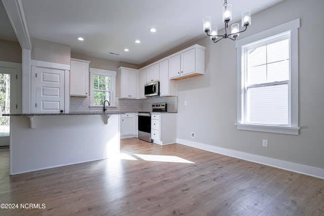 kitchen with white cabinetry, stainless steel appliances, a healthy amount of sunlight, and light hardwood / wood-style floors