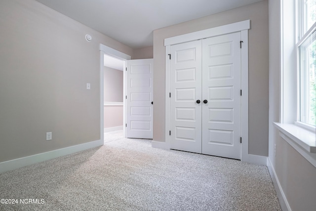 unfurnished bedroom featuring light carpet and a closet