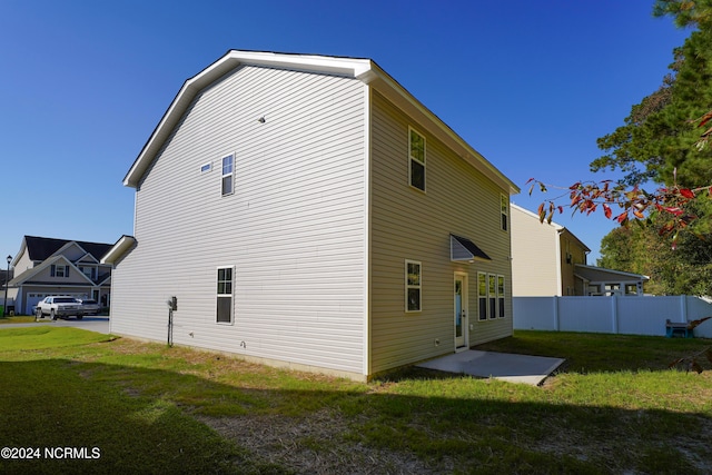 back of house with a patio and a lawn