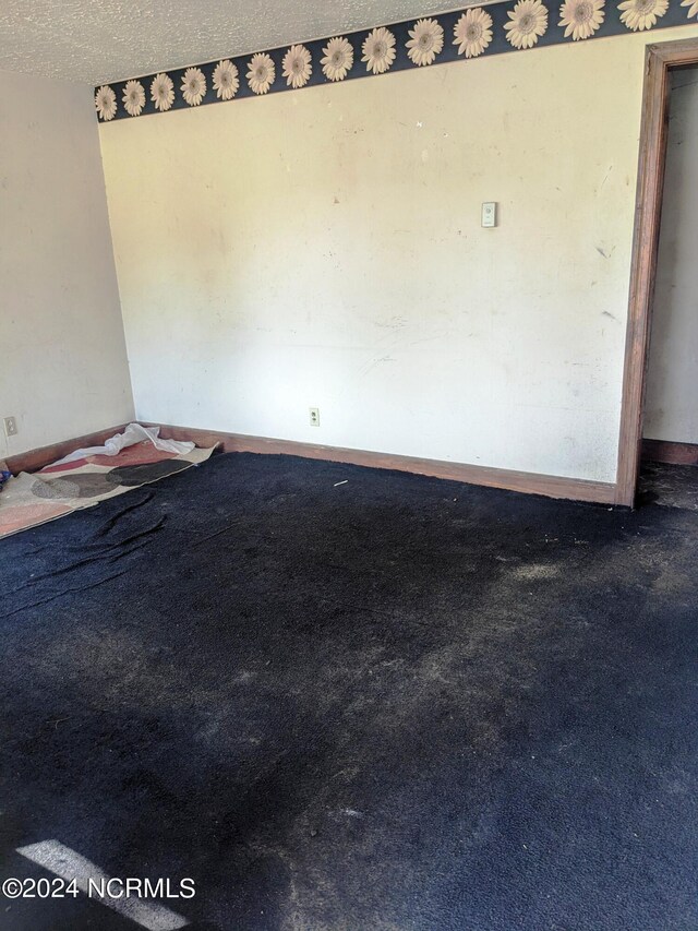 carpeted empty room featuring a textured ceiling