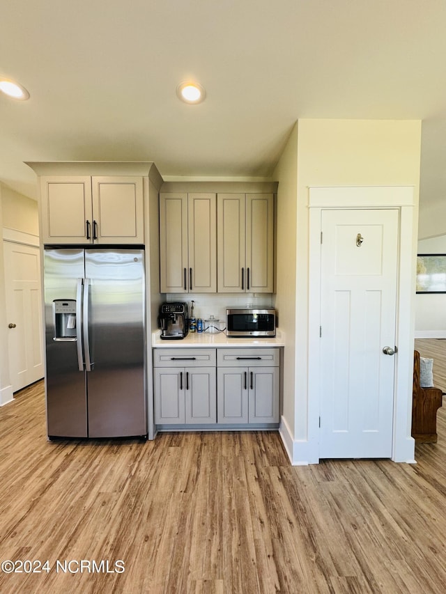 kitchen featuring stainless steel appliances, light hardwood / wood-style floors, and gray cabinetry