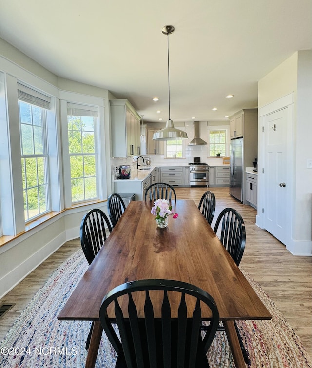 dining space with a wealth of natural light, sink, and light hardwood / wood-style floors