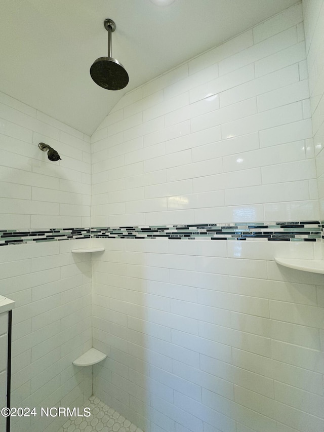 bathroom with tiled shower and lofted ceiling