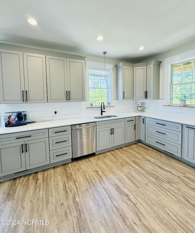 kitchen with dishwasher, light hardwood / wood-style floors, sink, and decorative light fixtures