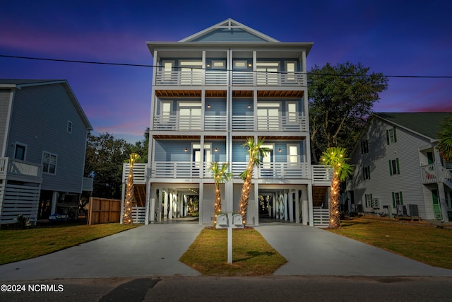 beach home featuring a lawn, central air condition unit, a balcony, and a carport