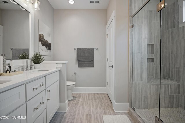 bathroom featuring dual vanity, toilet, tile floors, and a shower with door