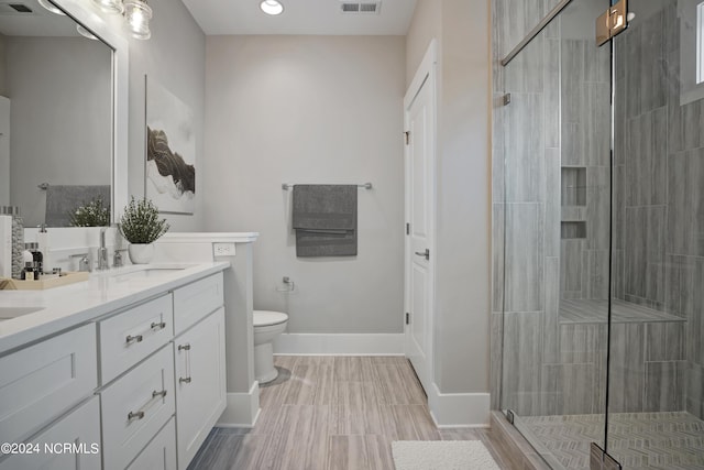 bathroom with vanity, toilet, and a shower with door