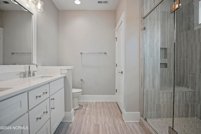 bathroom featuring tile flooring, vanity, toilet, and a shower with door