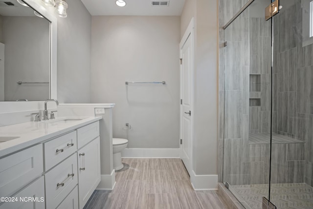 bathroom with vanity, a shower with door, and toilet