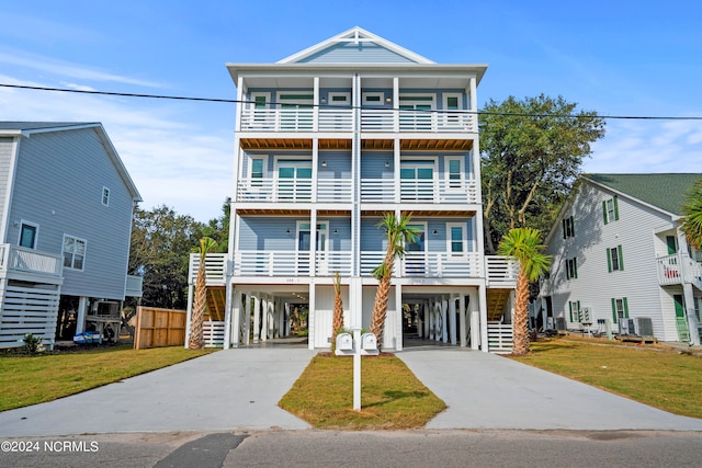 coastal inspired home with a front lawn, a carport, and a balcony