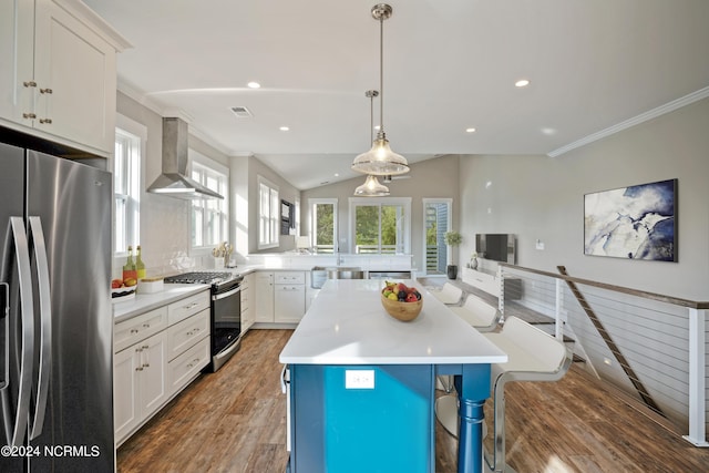 kitchen with a breakfast bar, white cabinetry, a kitchen island, wall chimney range hood, and stainless steel appliances