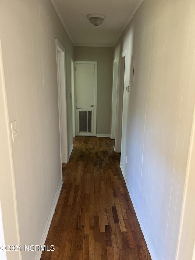 hallway with ornamental molding, dark wood-type flooring, visible vents, and baseboards