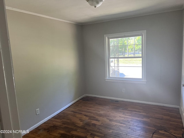 unfurnished room with ornamental molding, dark wood finished floors, visible vents, and baseboards