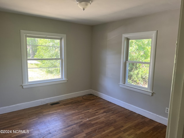 spare room with dark wood-style floors, visible vents, and a wealth of natural light