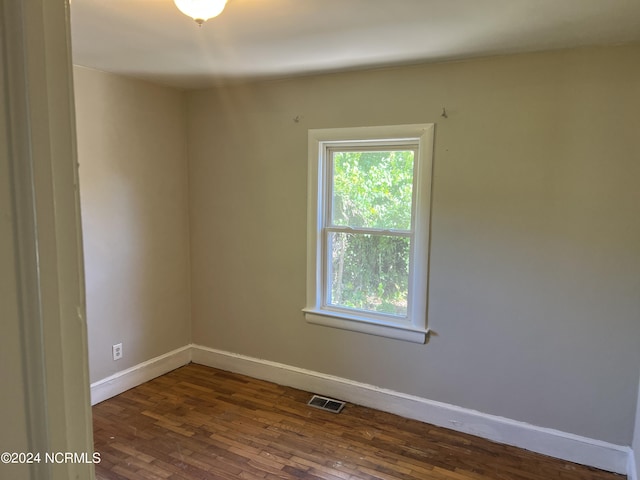 unfurnished room featuring baseboards, visible vents, and dark wood-style flooring