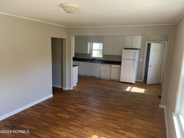 kitchen with dark countertops, white appliances, a sink, and baseboards