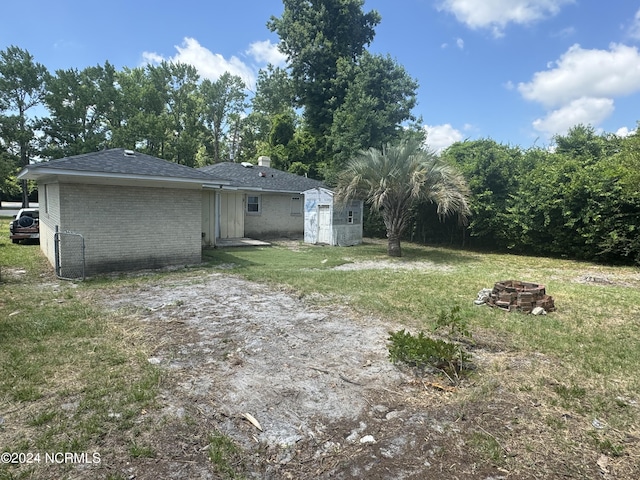 view of yard with a fire pit, a storage shed, and an outbuilding