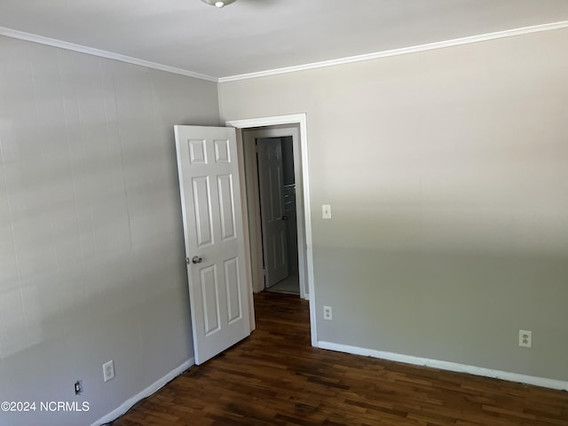 empty room with dark wood-style flooring, crown molding, and baseboards