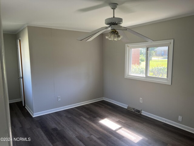 empty room featuring ornamental molding, dark wood-style flooring, visible vents, and baseboards