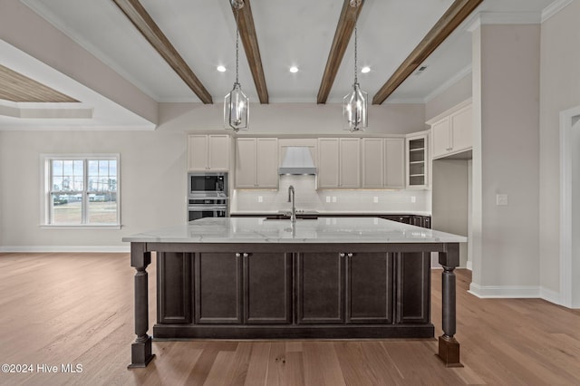 kitchen featuring light stone countertops, stainless steel appliances, a spacious island, and custom exhaust hood