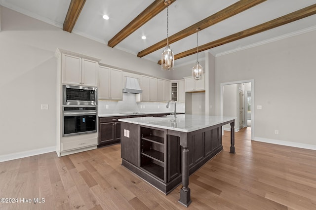 kitchen featuring a kitchen island with sink, white cabinets, oven, hanging light fixtures, and beamed ceiling