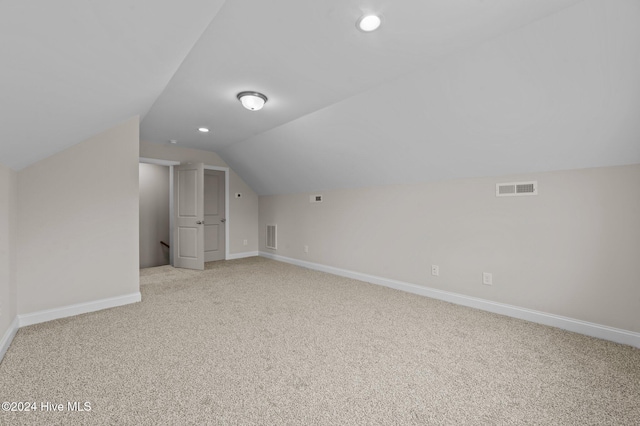 additional living space featuring light carpet and vaulted ceiling