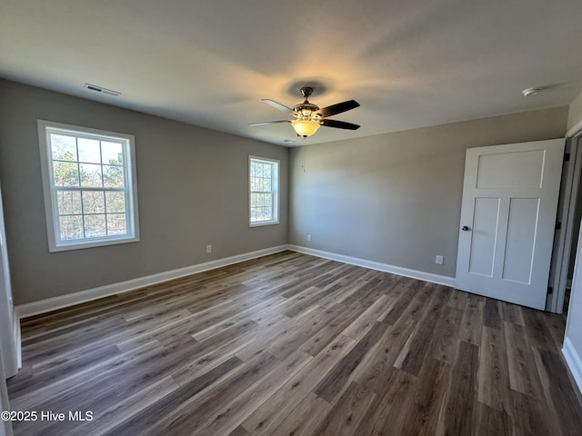 unfurnished room featuring ceiling fan, plenty of natural light, and dark wood-type flooring