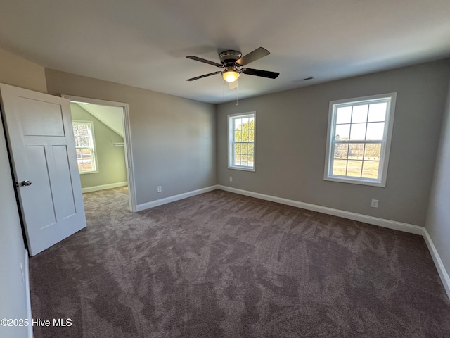 spare room with a wealth of natural light and dark colored carpet