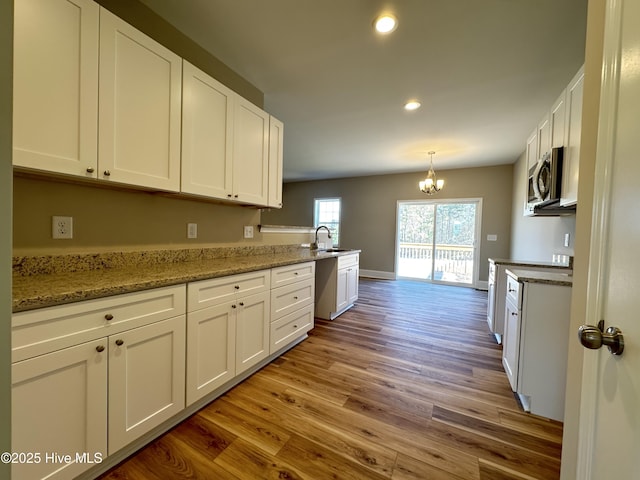 kitchen featuring sink, white cabinets, light hardwood / wood-style flooring, and an inviting chandelier